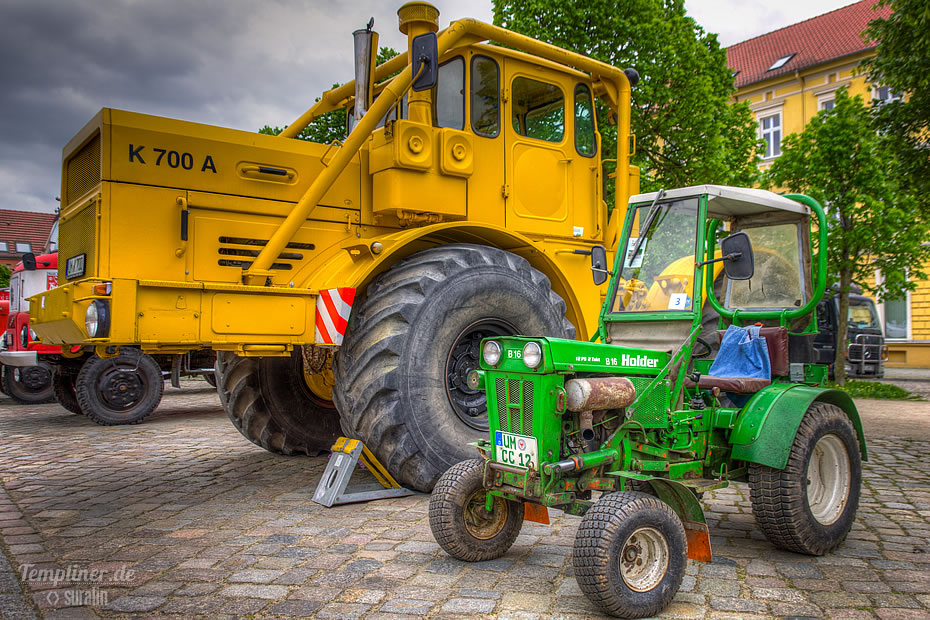 Große Landmaschine und kleiner Traktor auf dem Markt in Templin nebeneinander